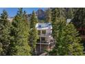 Exterior view of a multi-story home featuring multiple balconies surrounded by lush trees with mountain views at 4778 Knotty Pine Way, Las Vegas, NV 89124