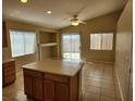 Eat-in kitchen boasts an island, bright lighting, neutral tile flooring, and a sliding glass door to the backyard at 5605 Midnight Breeze St, North Las Vegas, NV 89081