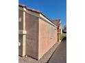 Side view of a stucco home with a decorative trim, showing a narrow walkway and low-maintenance gravel at 8900 Big Bear Pines Ave, Las Vegas, NV 89143