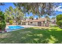Spacious backyard featuring a sparkling swimming pool, lush lawn, covered patio, and secure fencing at 2504 La Solana Way, Las Vegas, NV 89102