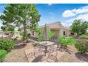 Backyard featuring a table with chairs, desert landscaping, and a mature shade tree at 2504 Libretto Ave, Henderson, NV 89052