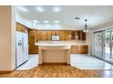 Bright kitchen featuring a center island, wood cabinetry, and a sliding glass door leading to the backyard at 3640 Snowy Pines St, Las Vegas, NV 89147