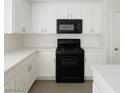 Well-lit kitchen featuring white cabinets, countertops, and modern black appliances at 520 Shire Hall St, Las Vegas, NV 89178