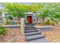 Inviting front entrance with stone steps, desert landscaping, and a gorgeous wood door at 8 Meadowhawk Ln, Las Vegas, NV 89135