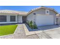 Close-up of a home featuring desert landscaping, green grass, and a two-car garage at 842 Envoy Cir, Henderson, NV 89002