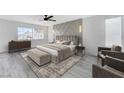 Comfortable main bedroom featuring a large window, patterned accent wall, and sitting area at 9541 Summersweet Ct, Las Vegas, NV 89123