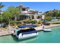 Luxury waterfront home with private dock and boat on a sunny day, showcasing waterfront living at 8725 Newport Isle Ct, Las Vegas, NV 89117