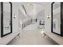 Grand foyer with a curved staircase, chandelier, glossy tile flooring, and stylish decor at 9605 Verlaine Ct, Las Vegas, NV 89145