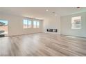 Bright living room featuring hardwood flooring, multiple windows providing natural light, and a sleek fireplace at 9842 Lost Horse Ave, Las Vegas, NV 89178