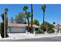 Traditional single-story home with mature palm trees, a two-car garage, and a well-kept lawn at 349 Esquina Dr, Henderson, NV 89014
