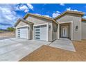 Close-up of home featuring a three-car garage, desert landscaping, and stylish exterior lighting at 4801 Stoneham, Pahrump, NV 89061