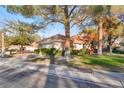 Well-maintained property featuring lush green grass, mature shade trees and lovely red outdoor seating at 5058 Crooked Stick Way, Las Vegas, NV 89113