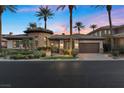 Elegant desert home featuring lush landscaping, a stone turret, and a brick driveway leading to a two-car garage at 51 Avenida Sorrento, Henderson, NV 89011