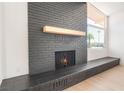 Close-up of the brick fireplace with wooden mantel and adjacent window for natural light at 6205 Hargrove Ave, Las Vegas, NV 89107