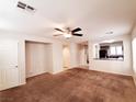 Spacious living room featuring neutral walls, brown carpet, a ceiling fan, and an archway to the kitchen at 9069 Tantalizing Ave, Las Vegas, NV 89149