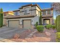 Two-story home with a three car garage, neutral stucco exterior with stone accents and desert landscaping at 11417 Rock Cove Way, Las Vegas, NV 89141