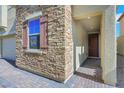 Close up of a charming home's exterior featuring stone veneer, window shutters, and a covered entryway at 152 Walkinshaw Ave, Las Vegas, NV 89148