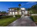 Elegant two-story home features a meticulously landscaped yard, a stately entrance, and a circular driveway at dusk at 2058 Troon Dr, Henderson, NV 89074