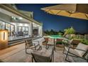 Inviting backyard with a covered patio, cozy seating areas, and a view of the sparkling swimming pool at night at 2058 Troon Dr, Henderson, NV 89074