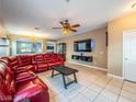 Inviting living room featuring a plush red sofa, tile flooring, and a wall-mounted TV at 268 Copper Glow Ct, Henderson, NV 89074