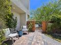 Cozy outdoor seating area with gray chairs, stone flooring, lush plants, and a private gated entrance at 396 Blackstone River Ave, Las Vegas, NV 89148