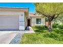 Charming home features a well-manicured lawn and a lovely desert tree in the front yard at 42 Glade Water Dr, Henderson, NV 89052