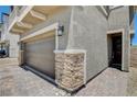 Close up of a two-car garage with stone columns on either side of the door and a brick driveway at 4240 Spring Storm Ave, North Las Vegas, NV 89081