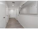 Hallway with wood-look floors, white walls, recessed lighting, white doors, and a large mirror at 4976 Quiet Morning St, Las Vegas, NV 89122