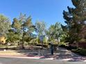 Landscaped community common area with mature trees, shrubs, and a walking path at 5216 Loma Verde Ave, Las Vegas, NV 89108