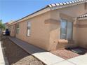 Tan home exterior with tidy desert landscaping and a concrete walkway at 6470 Shining Sand Ave, Las Vegas, NV 89142