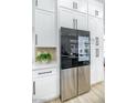 Bright kitchen features stainless steel refrigerator and ample white cabinets with modern, black hardware at 9813 Folsom Dr, Las Vegas, NV 89134