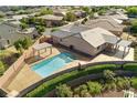 Aerial view displays a backyard oasis with a refreshing pool, adjacent spa, covered patio, and green landscaping at 10302 Artful Stone Ave, Las Vegas, NV 89149