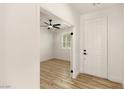 Bright entryway featuring a white door, light wood flooring, and an open view into another room at 10302 Artful Stone Ave, Las Vegas, NV 89149
