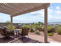 Covered patio with chairs and views of the wrought iron fenced backyard with mature landscaping at 3088 Evening Mist Ave, Henderson, NV 89052