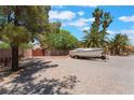 Large, gravel lot with space for RV or boat parking behind a fence and mature trees at 4530 W Shelbourne Ave, Las Vegas, NV 89139