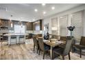 Open-concept dining area featuring wood floors, modern lighting, and a view into the adjacent kitchen at 8175 Caldera Creek St, Las Vegas, NV 89113