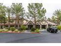 Clubhouse with stucco walls, a tile roof, arched entrances, and several palm trees in front at 2200 S Fort Apache Rd # 2217, Las Vegas, NV 89117