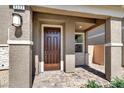 A covered entryway with stone columns, a dark wood door and a brick pathway at 4533 Queens Hill St, North Las Vegas, NV 89031