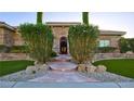 Inviting front entrance with mature landscaping, stone accents, and walkway with artificial turf at 6120 Kings Brook Ct, Las Vegas, NV 89149