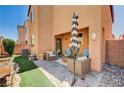 Inviting backyard featuring a covered patio, artificial grass, rock landscaping, and a shady umbrella at 7704 Lots Hills Dr, Las Vegas, NV 89179