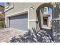 Home exterior showcasing the front entrance, brick driveway, and a gray two-car garage at 7720 Houston Peak St, Las Vegas, NV 89166