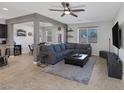 Open living room with gray sofa, dark ottoman, ceiling fan, and tile flooring at 7720 Houston Peak St, Las Vegas, NV 89166