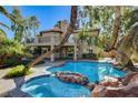Beautiful backyard pool with rock accents, lush landscaping, and a covered patio for outdoor entertaining at 902 Cripple Creek Ct, Henderson, NV 89014