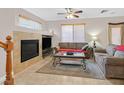Comfortable living room with fireplace, ceiling fan, and natural light from windows at 10601 Lessona St, Las Vegas, NV 89141