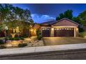 Charming home exterior with a three-car garage, desert landscaping, and illuminated entrance at 2786 Scotts Valley Dr, Henderson, NV 89052