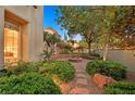 Landscaped backyard features a stone fire pit surrounded by lush greenery and a stone walkway at 1404 Reisling Ct, Las Vegas, NV 89144