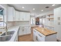Bright kitchen with white cabinets, a butcher block island, stainless steel sink, and views of the living area at 2107 Fountain Springs Dr, Henderson, NV 89074