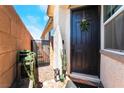 A welcoming front entryway with a black door, decorative wreath, and charming potted plants on a brick porch at 2845 Mincio St, Henderson, NV 89044