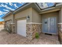 Welcoming front entrance with stone accents, double doors, a white garage door, and manicured landscaping at 365 Sapphire Rock Ave, Las Vegas, NV 89183