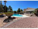 Beautiful backyard with a sparkling pool, desert landscaping, covered patio, and ample space for outdoor living at 4542 Amber Canyon Ln, Las Vegas, NV 89129